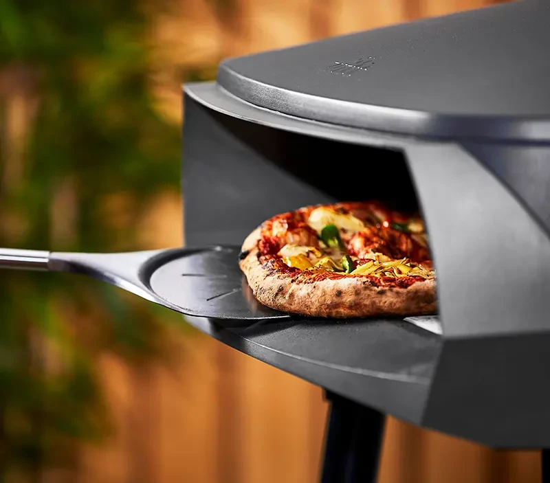 Nært bilde av pizza på vei ut av pizzaovn